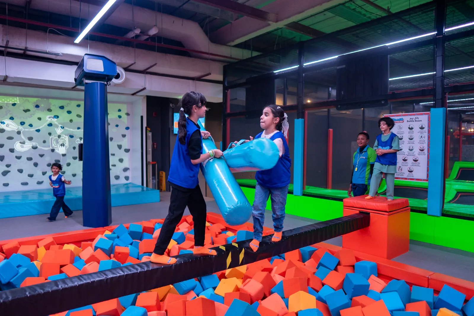 Girls battling on the beam over a foam pit at Trampo Dubai Mall