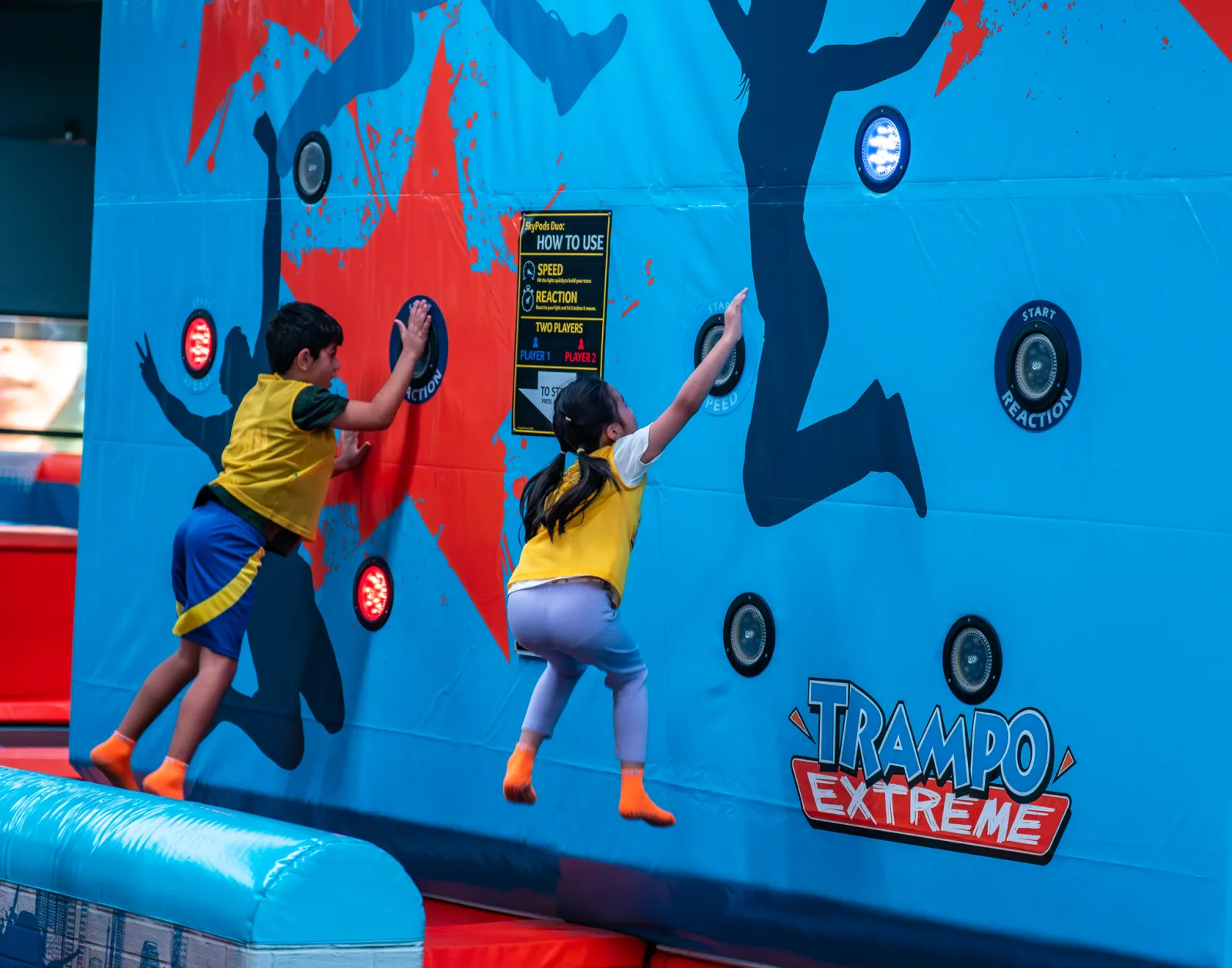 Boy and girl competing side by side on the interactive wall at Trampo