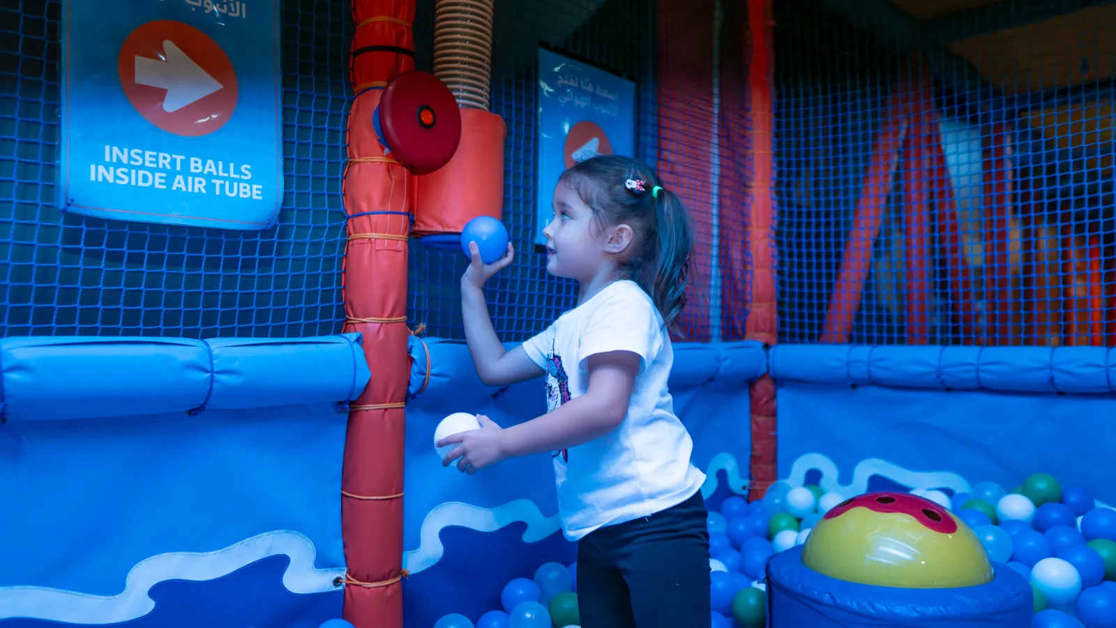 Girl inserting balls into the air tube at Trampo soft play
