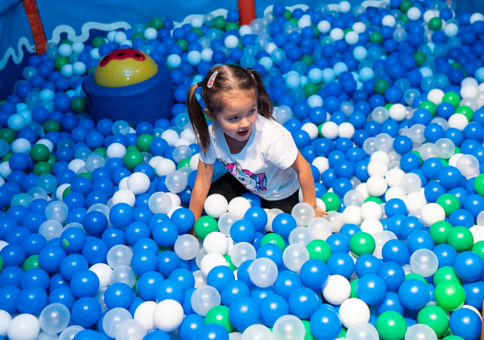 Girl crawling through the ball pit at Trampo soft play