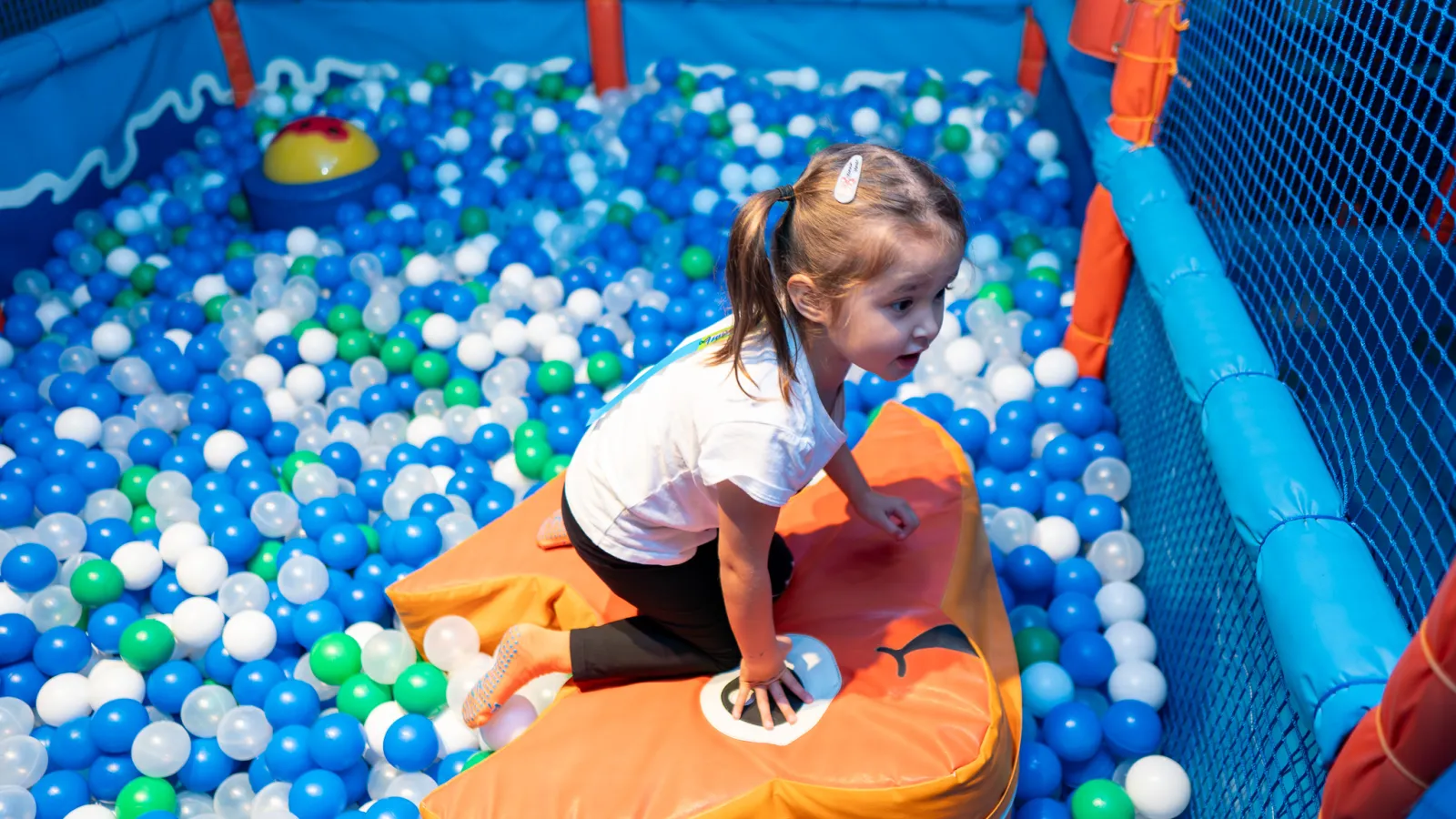 Girl climbing on inflatable in the ball pit at Trampo