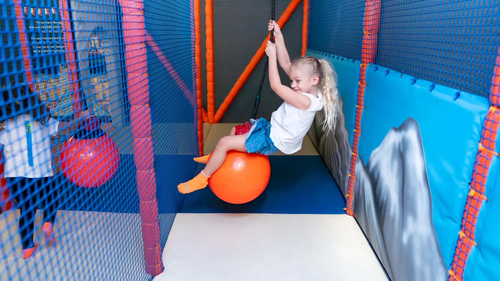 Girl riding the rope swing in Trampo soft play area