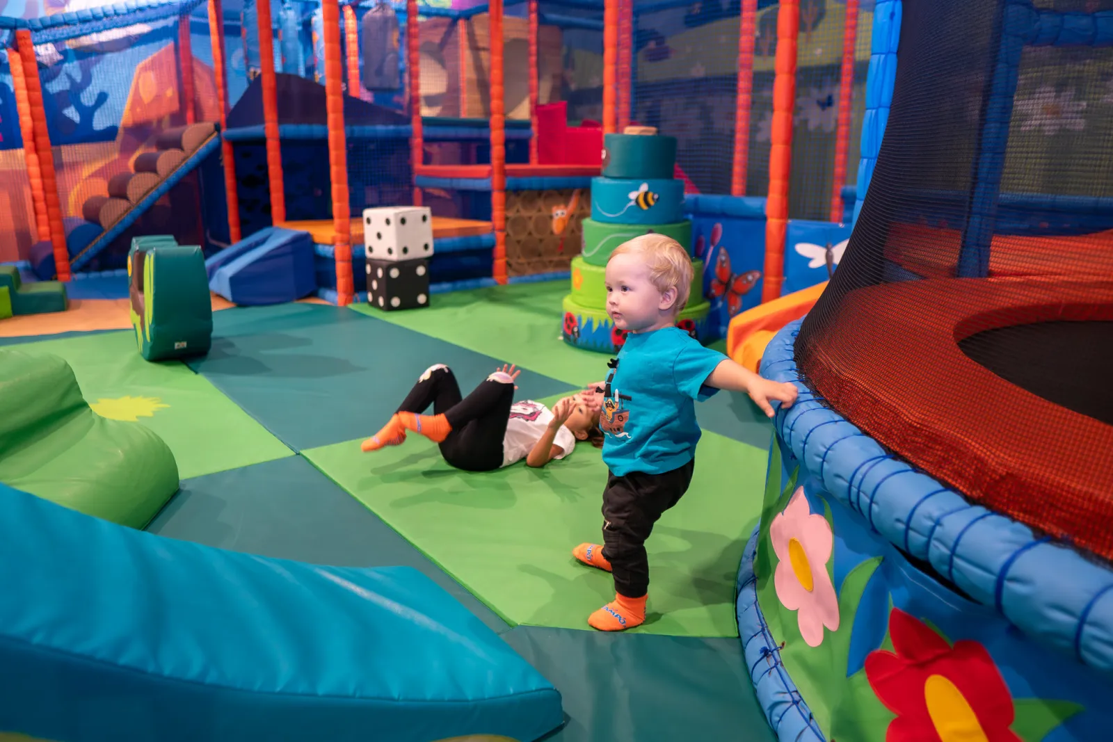 Toddler exploring the soft play area with mini trampoline at Trampo