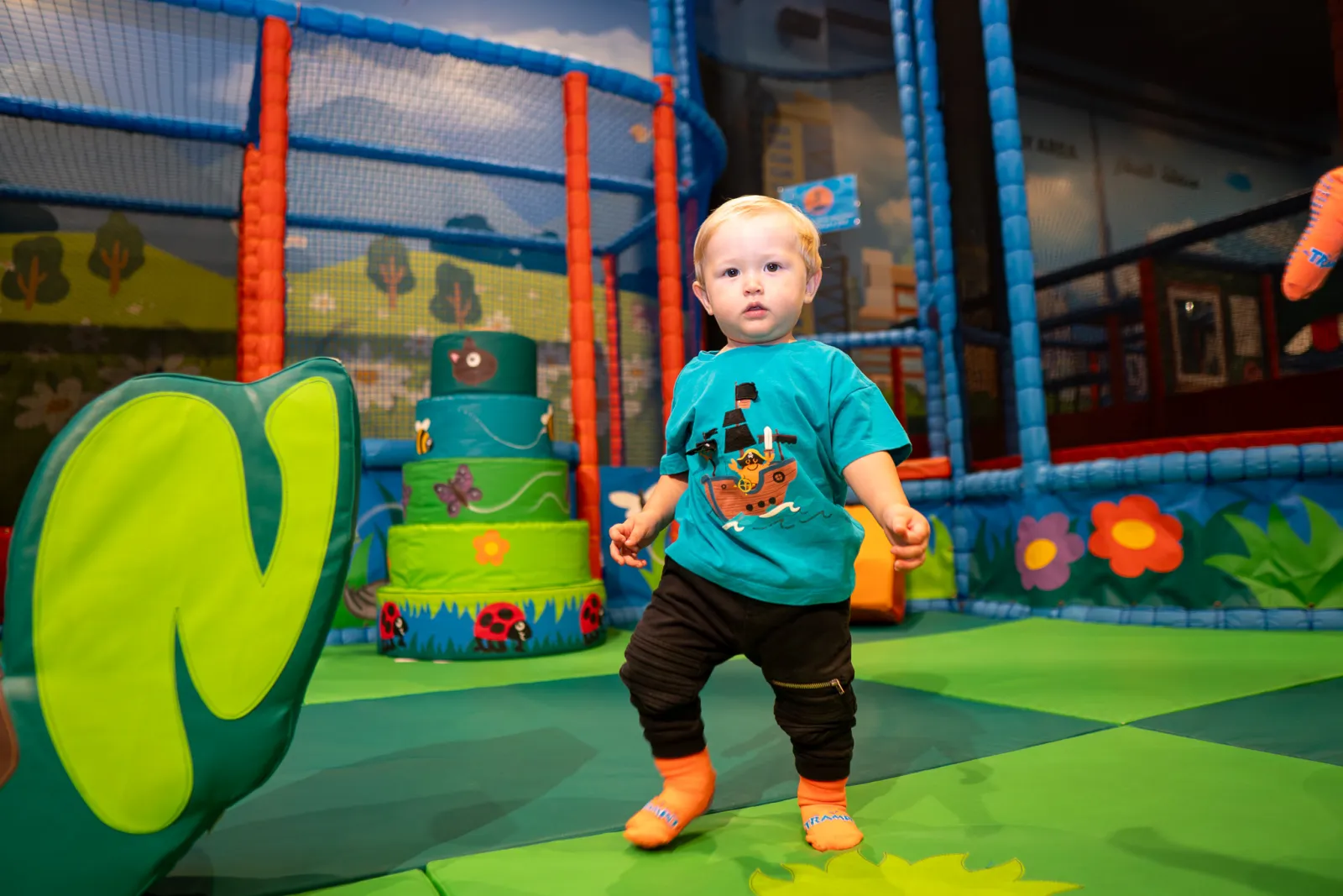 Toddler standing in the colorful play area at Trampo