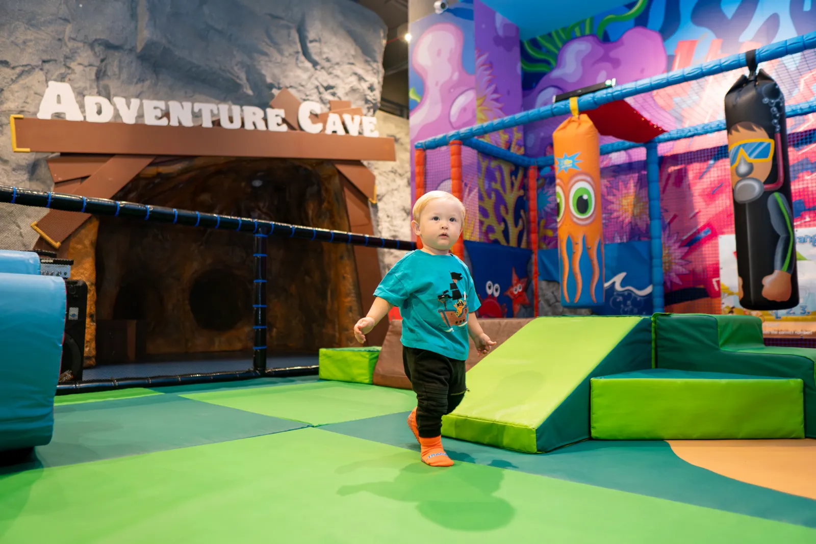 Toddler walking near the Adventure Cave with soft ramps at Trampo