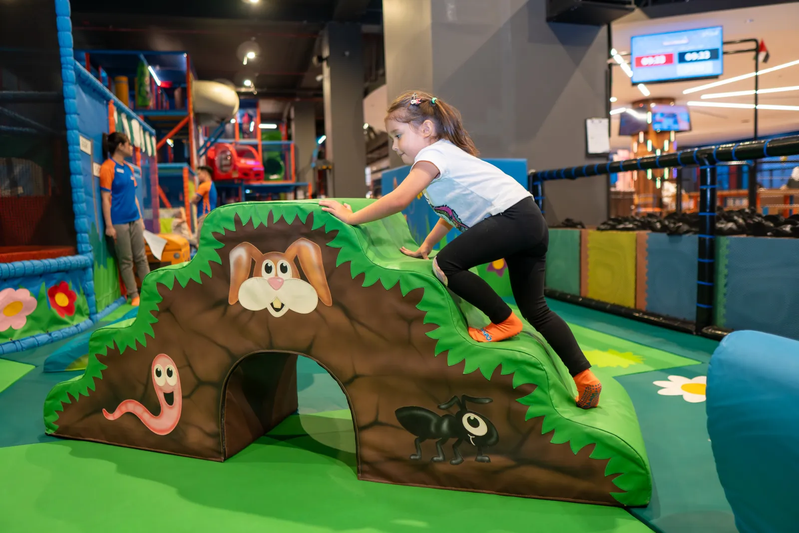 Girl climbing a soft bunny-themed hill in the toddler area at Trampo