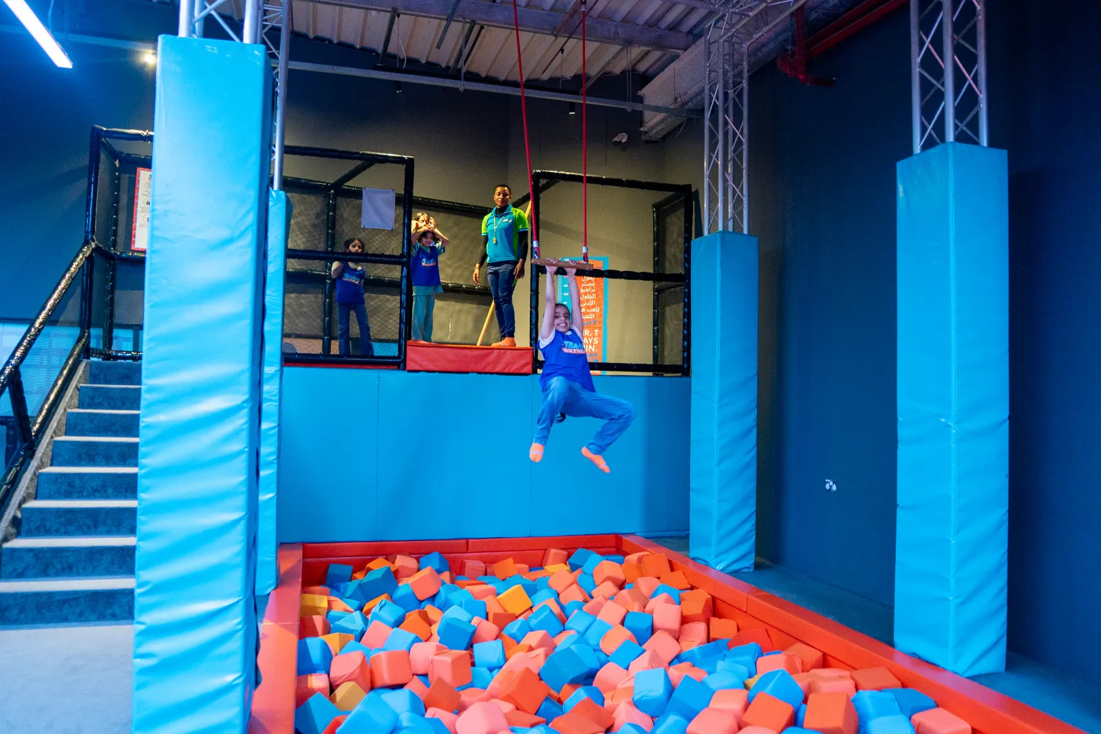 Person hanging from the trapeze above the foam pit at Trampo